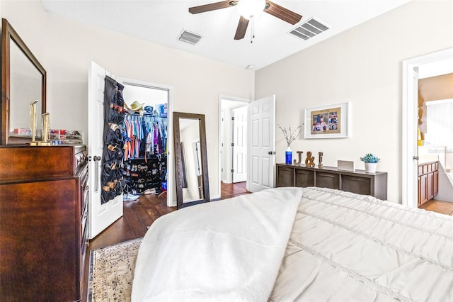 bedroom with ensuite bathroom, dark hardwood / wood-style flooring, a walk in closet, ceiling fan, and a closet