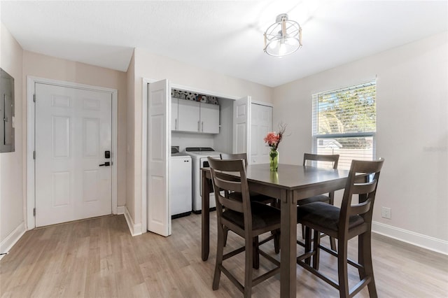 dining space featuring baseboards, light wood-style floors, electric panel, and washing machine and dryer