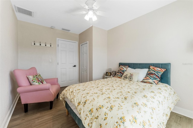 bedroom featuring wood finished floors, a closet, ceiling fan, baseboards, and visible vents