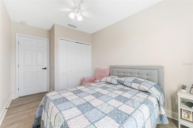 bedroom featuring a closet, light wood-type flooring, a ceiling fan, visible vents, and baseboards