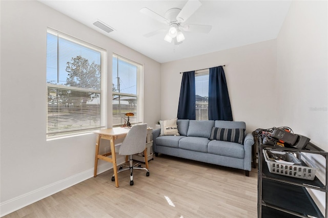 office area featuring baseboards, light wood-type flooring, a wealth of natural light, and ceiling fan