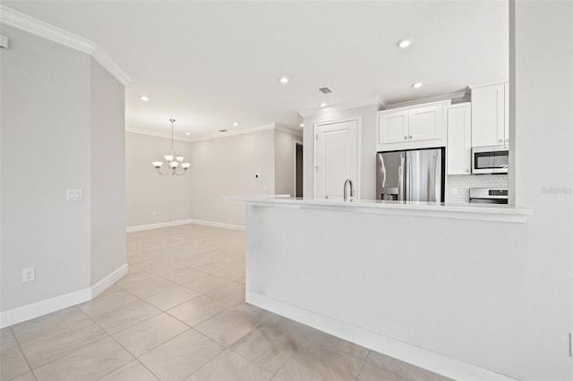 kitchen with light tile patterned floors, an inviting chandelier, crown molding, white cabinets, and appliances with stainless steel finishes