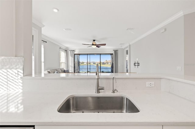 kitchen featuring light stone countertops, sink, ceiling fan, dishwashing machine, and ornamental molding