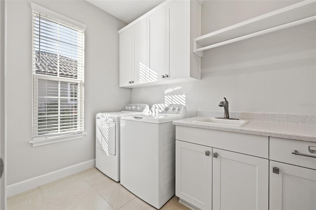 clothes washing area with cabinets, light tile patterned floors, washer and clothes dryer, and sink