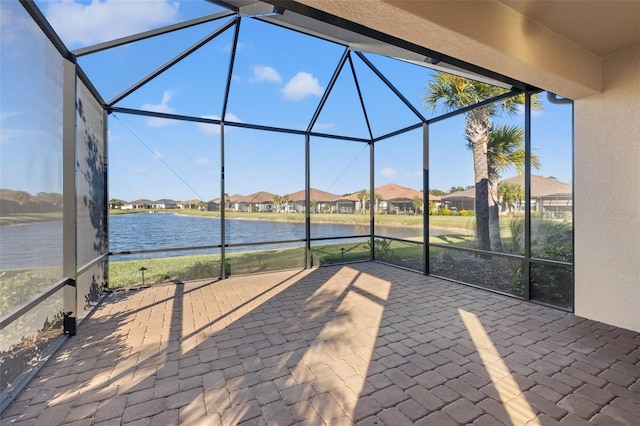 view of patio with a water view and glass enclosure