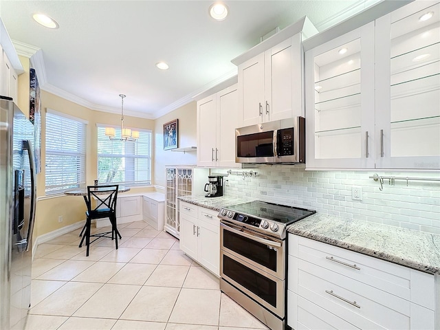 kitchen with stainless steel appliances, light tile patterned floors, pendant lighting, white cabinets, and ornamental molding