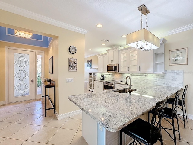 kitchen with kitchen peninsula, appliances with stainless steel finishes, a kitchen bar, pendant lighting, and white cabinetry