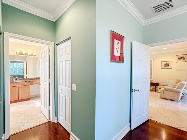 corridor with crown molding, sink, and light wood-type flooring