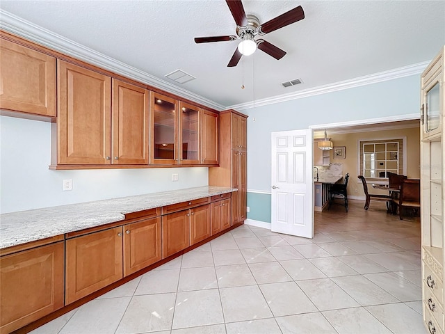 kitchen featuring ceiling fan, light stone countertops, a textured ceiling, light tile patterned floors, and ornamental molding