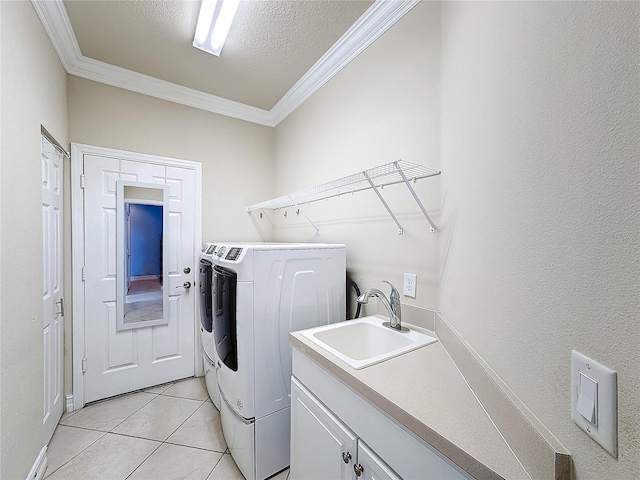 clothes washing area with cabinets, washer and clothes dryer, crown molding, sink, and light tile patterned floors