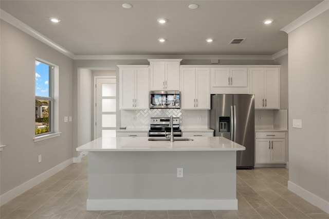 kitchen with sink, appliances with stainless steel finishes, a kitchen island with sink, decorative backsplash, and white cabinets