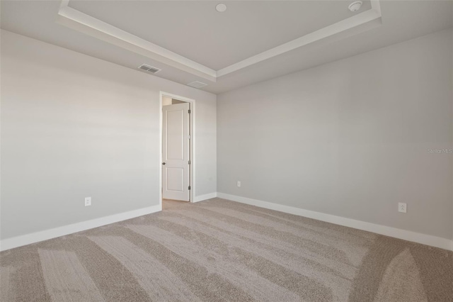 carpeted empty room featuring a raised ceiling