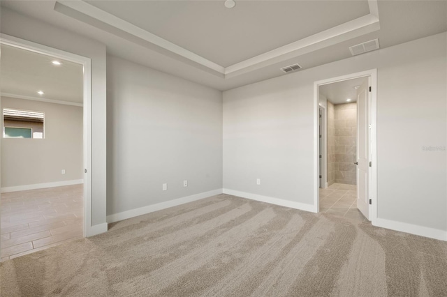 carpeted spare room featuring a tray ceiling