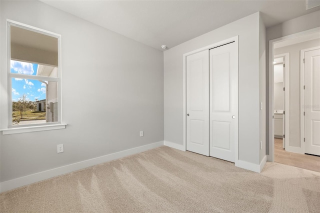 unfurnished bedroom featuring light colored carpet and a closet