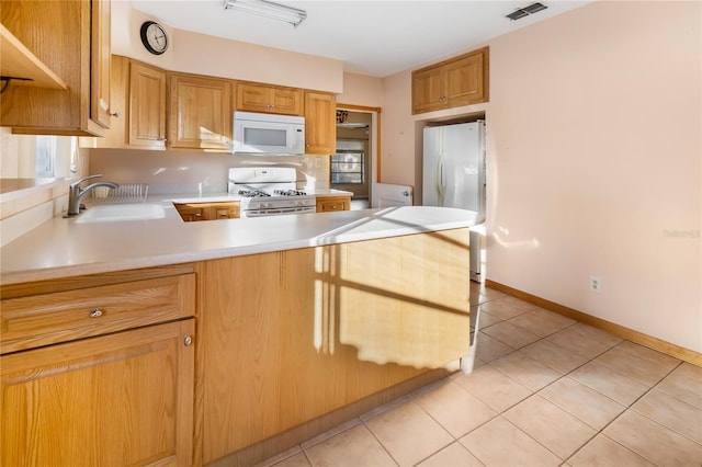 kitchen featuring kitchen peninsula, sink, light tile patterned floors, and white appliances