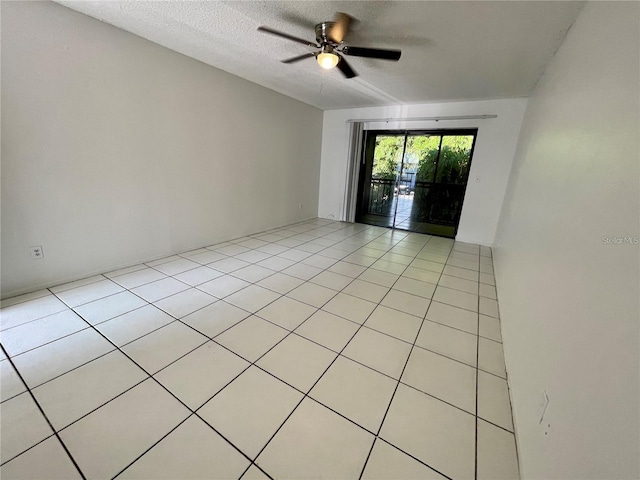 tiled empty room with ceiling fan and a textured ceiling