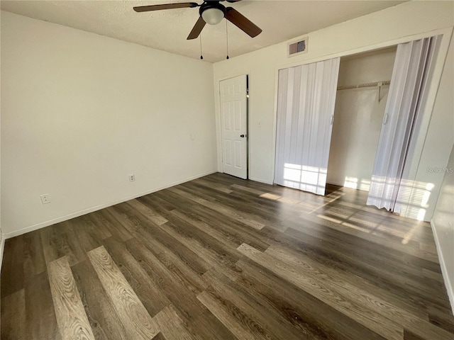 unfurnished bedroom featuring dark hardwood / wood-style flooring, ceiling fan, and a closet