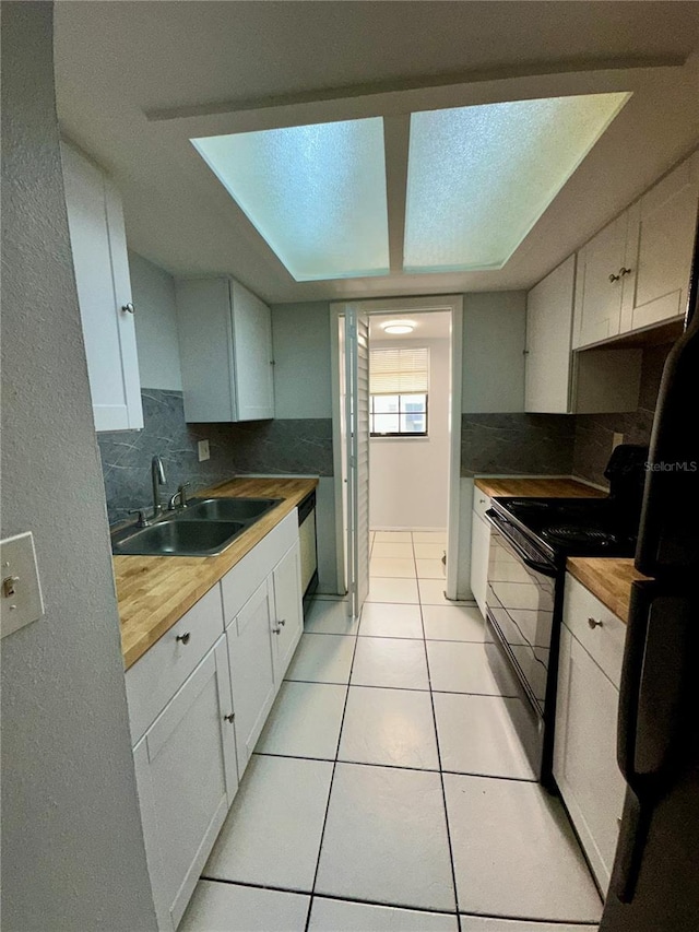 kitchen with white cabinetry, sink, and wood counters