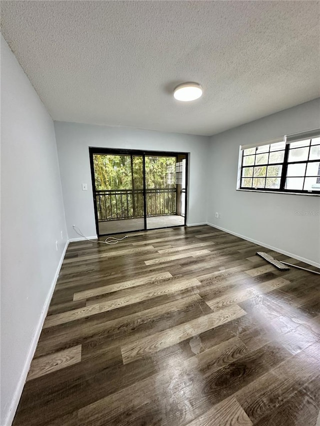 spare room featuring a textured ceiling, dark hardwood / wood-style floors, and a healthy amount of sunlight