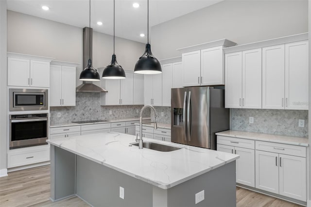 kitchen with sink, stainless steel appliances, an island with sink, pendant lighting, and white cabinets