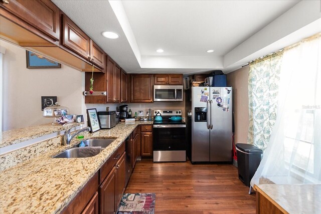 kitchen featuring sink, light stone countertops, dark wood-type flooring, and appliances with stainless steel finishes