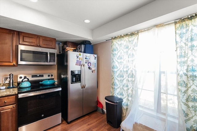 kitchen featuring light stone countertops, appliances with stainless steel finishes, and light hardwood / wood-style floors