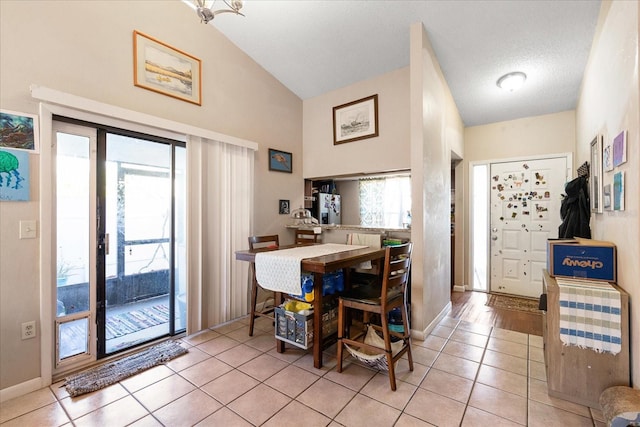 tiled dining area featuring a textured ceiling and high vaulted ceiling