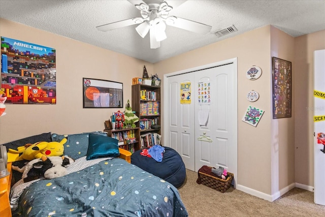 carpeted bedroom with a textured ceiling, a closet, and ceiling fan