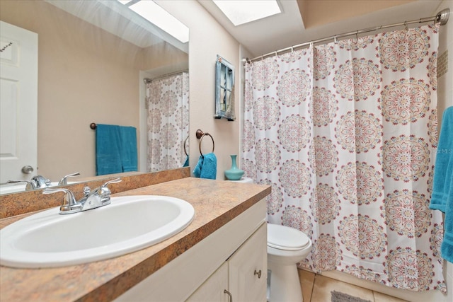 bathroom with tile patterned flooring, vanity, a skylight, and toilet