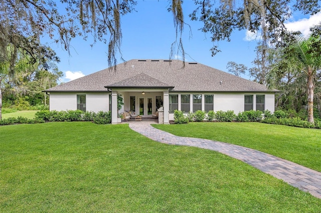 13430 Haflinger Way, Hudson, FL 34667 - rear view of house with french doors, a lawn, stucco siding, and roof with shingles
