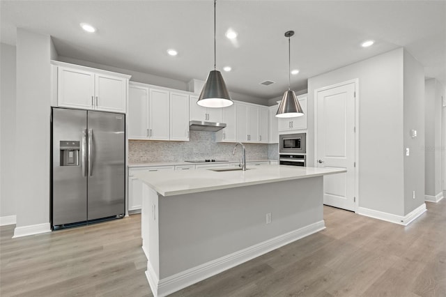 kitchen with white cabinets, light wood-type flooring, stainless steel appliances, and a center island with sink