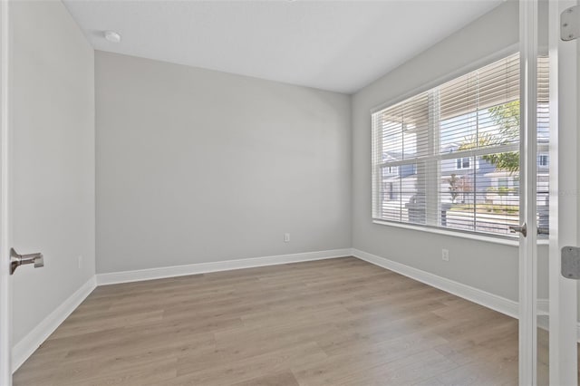 empty room featuring baseboards and light wood finished floors