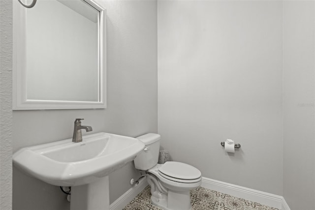 bathroom featuring a sink, tile patterned flooring, toilet, and baseboards