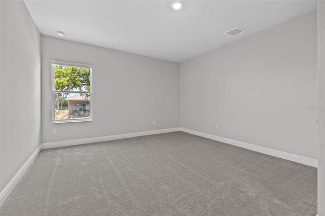 carpeted empty room featuring visible vents and baseboards