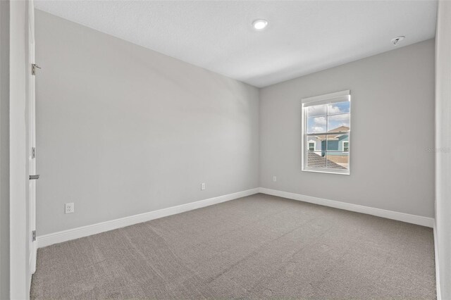 spare room featuring carpet and baseboards