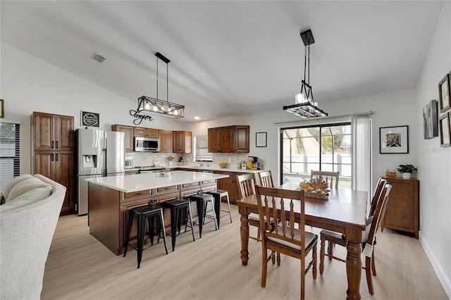 dining area with light hardwood / wood-style floors, lofted ceiling, and sink