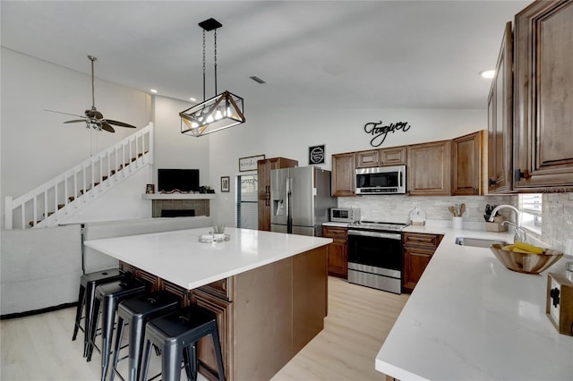 kitchen featuring sink, a center island, light hardwood / wood-style floors, and appliances with stainless steel finishes