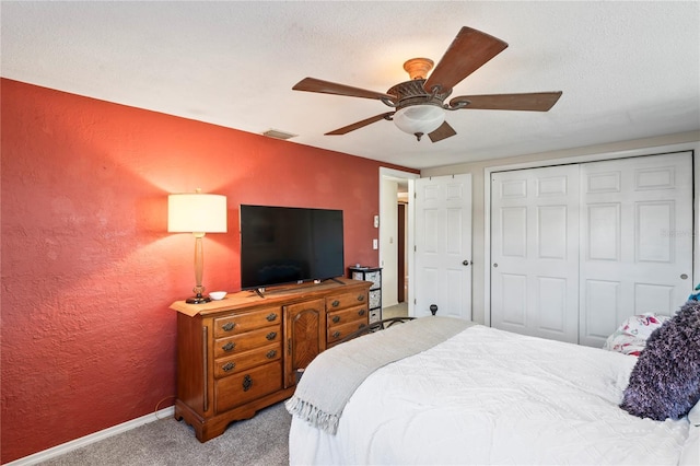 bedroom featuring a textured ceiling, light colored carpet, a closet, and ceiling fan