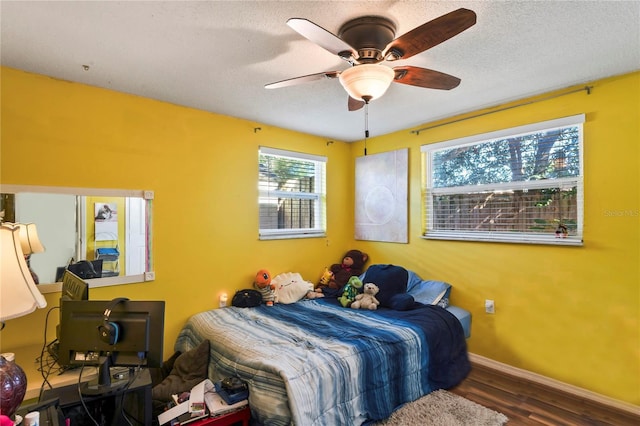 bedroom with a textured ceiling, dark hardwood / wood-style floors, and ceiling fan