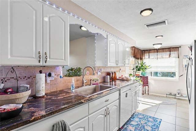 kitchen with decorative backsplash, white appliances, sink, light tile patterned floors, and white cabinetry