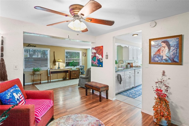 living room with ceiling fan, sink, and light hardwood / wood-style floors