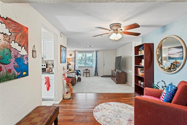 living room featuring ceiling fan, hardwood / wood-style floors, and a textured ceiling