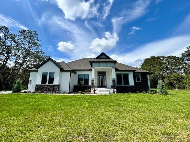 13400 Haflinger Way, Hudson, FL 34667 - view of front of house featuring stone siding, a front yard, and stucco siding
