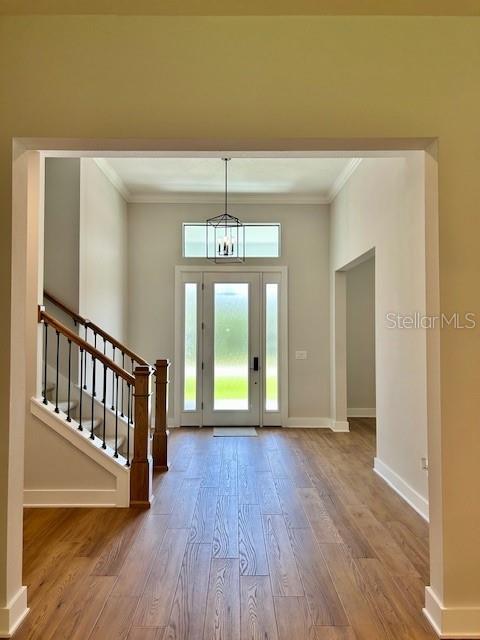 13400 Haflinger Way, Hudson, FL 34667 - entryway with crown molding, wood finished floors, stairway, and a chandelier