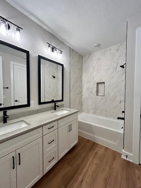 13400 Haflinger Way, Hudson, FL 34667 - full bathroom featuring a textured ceiling, double vanity, wood finished floors, and  shower combination