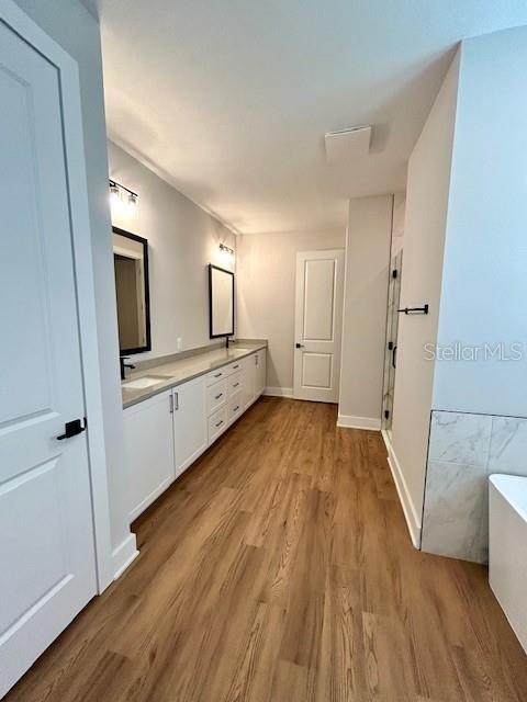 13400 Haflinger Way, Hudson, FL 34667 - bathroom with a freestanding tub, double vanity, and wood finished floors