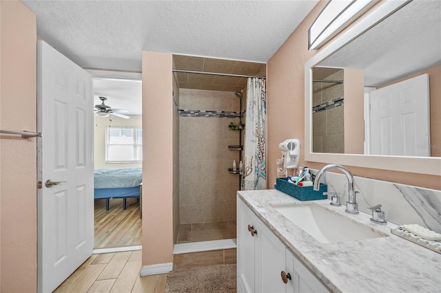 bathroom with ceiling fan, curtained shower, a textured ceiling, and vanity