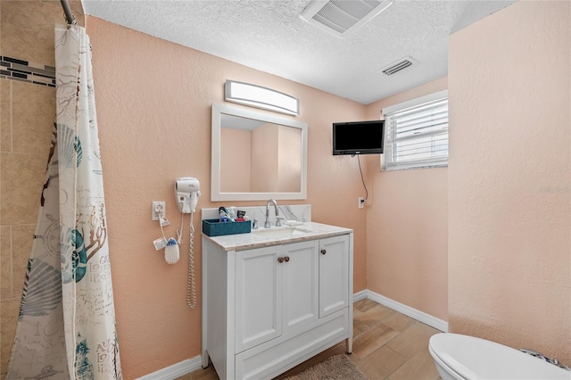 bathroom with a shower with curtain, hardwood / wood-style floors, a textured ceiling, toilet, and vanity