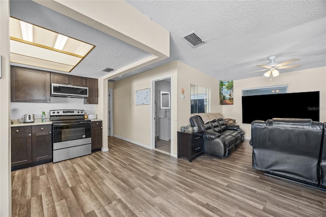 kitchen with dark brown cabinets, light hardwood / wood-style floors, and appliances with stainless steel finishes