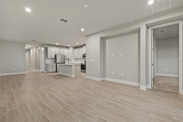 unfurnished living room with sink and light wood-type flooring